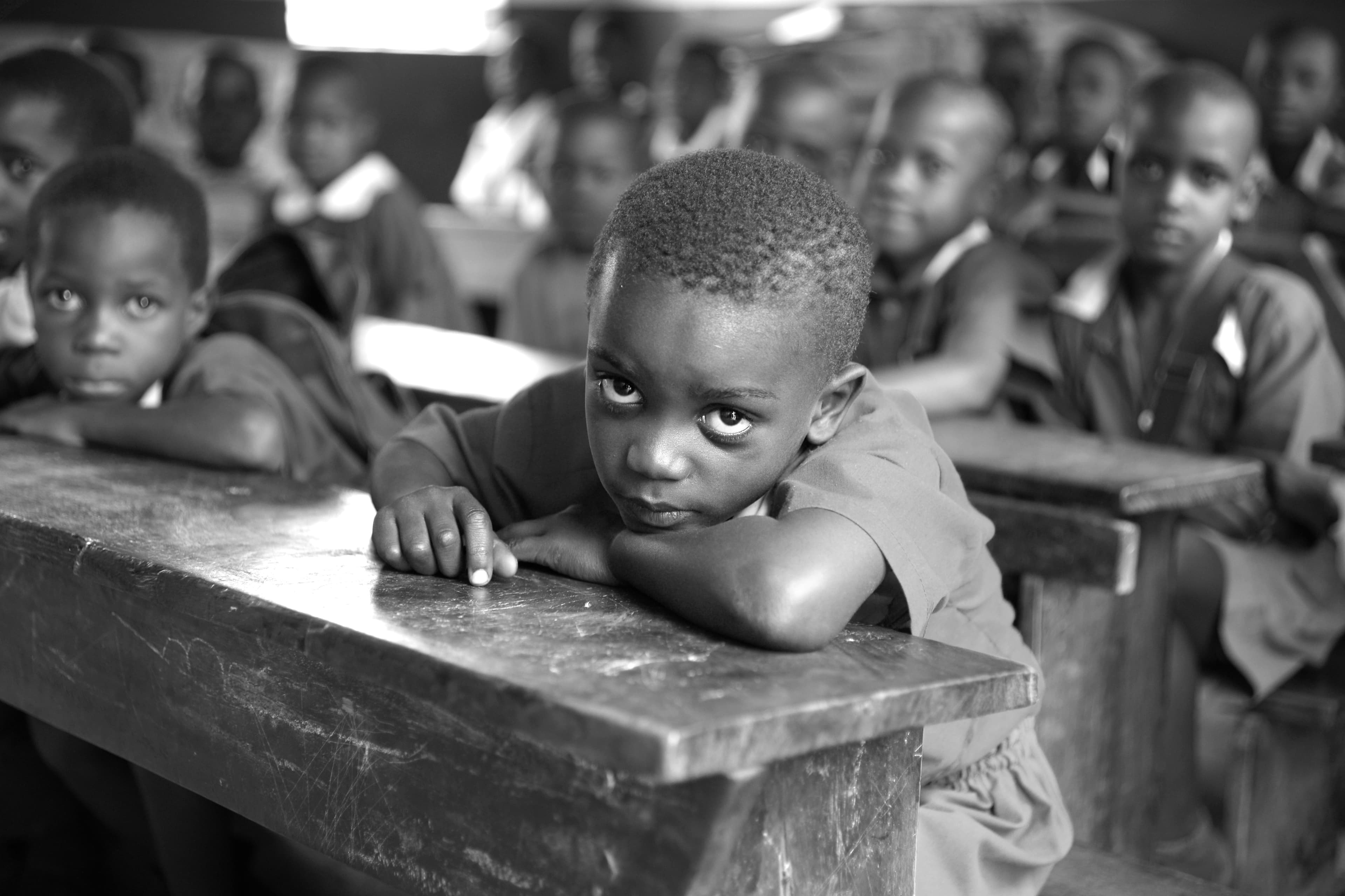 Young African children engaged in early learning in a nurturing classroom setting, with a teacher present.